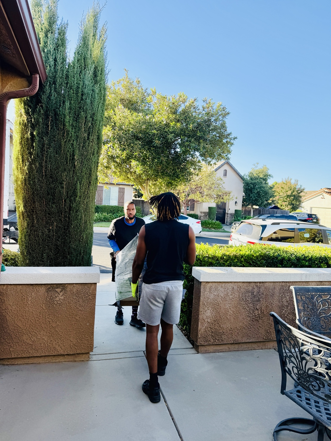 Pack And Go movers carrying protected furniture through a Fresno home's front entry